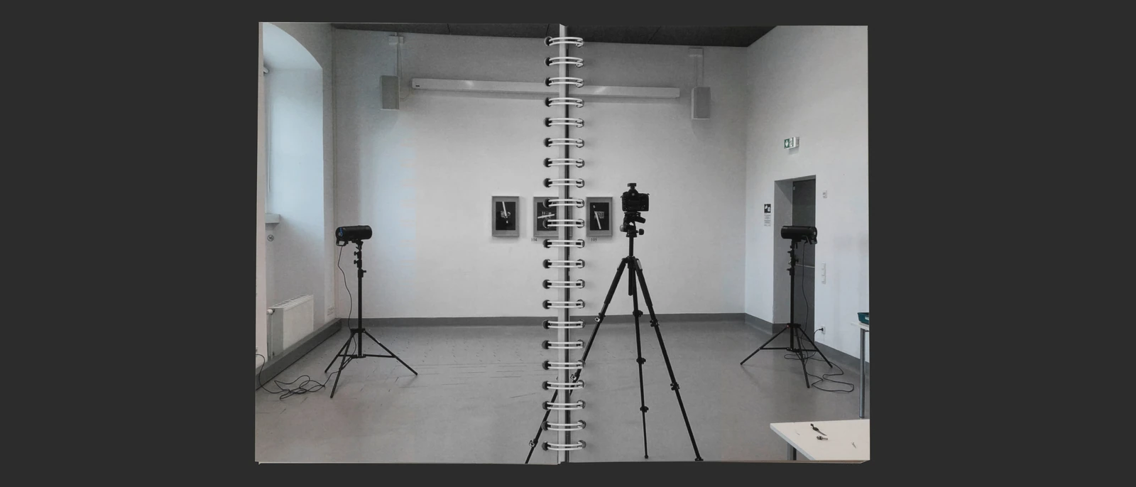 Open thesis spread showing a gallery space with cameras and framed works.