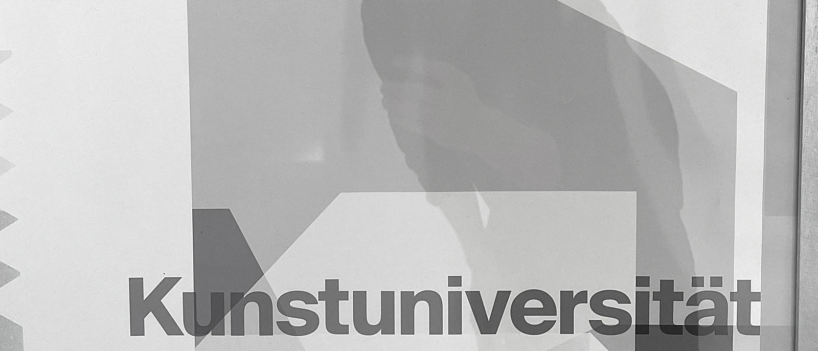 Detail of a translucent grey poster with a person's shadow behind it.