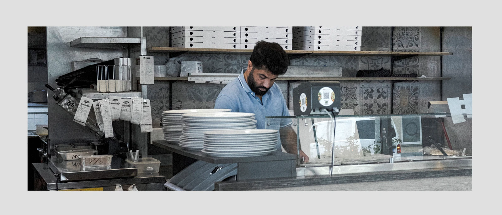 Restaurant worker behind the counter with stacks of plates.
