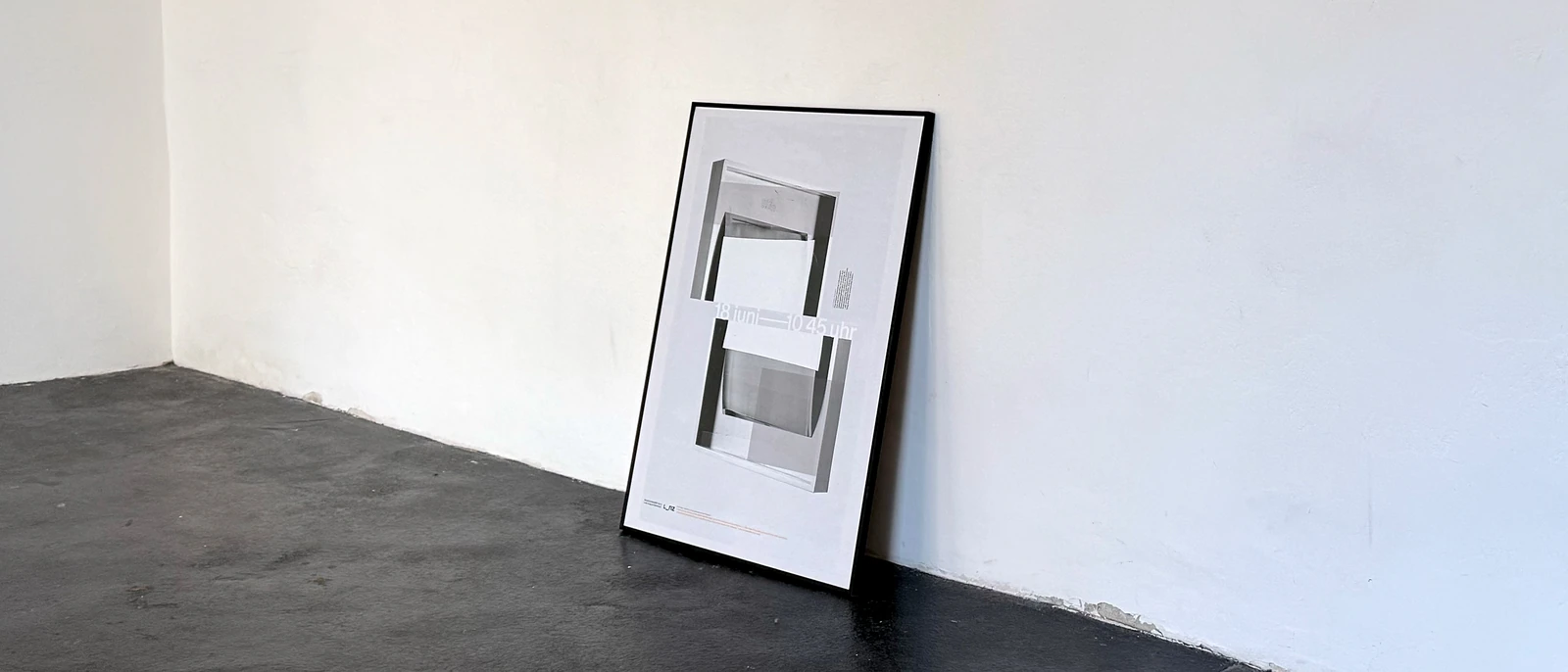 Framed presentation poster leaning against a white wall.