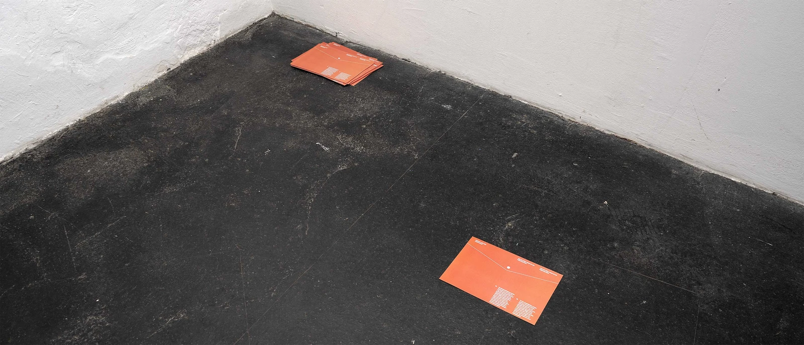 Orange handouts placed on a dark concrete floor.